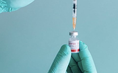 A person holding a vial and syringe.  
